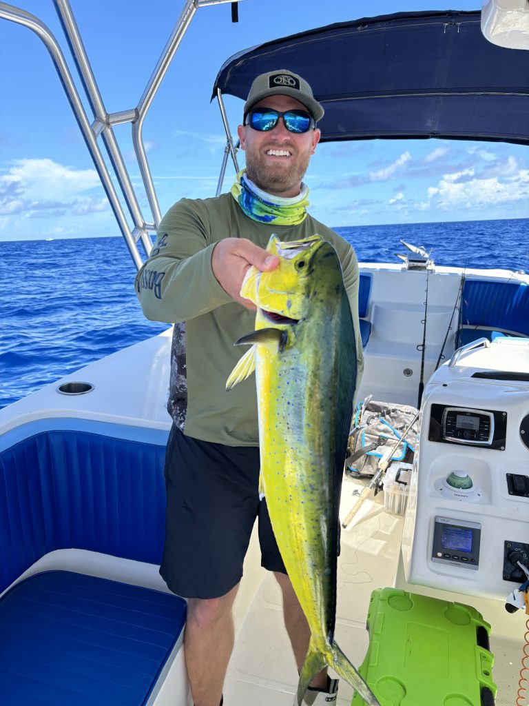 Large mahi mahi dolphin fish caught during summer fishing season in the Florida Keys. Sport fishing boat trolling offshore in the Florida Keys searching for mahi mahi. Man caught large Mahi Mahi in the Florida Keys. FloridaKeysVillas.com
