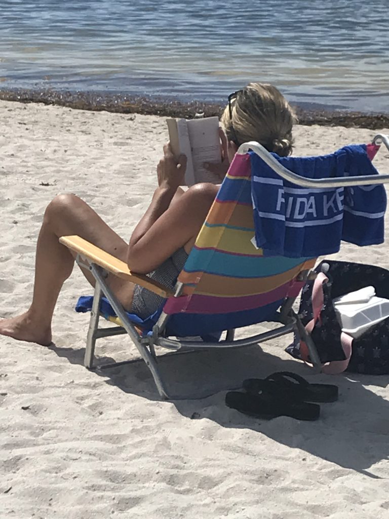 Sombrero Beach is quite calm and relaxing. Girl sunbathing and reading a book at the beach. FloridaKeysVillas.com