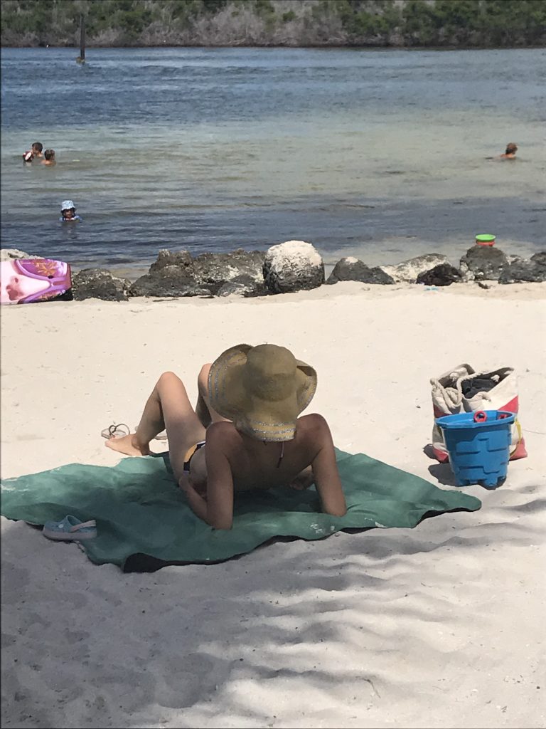 Girl Sunbathing and relaxing in the sun at Sombrero Beach Florida. FloridaKeysVillas.com