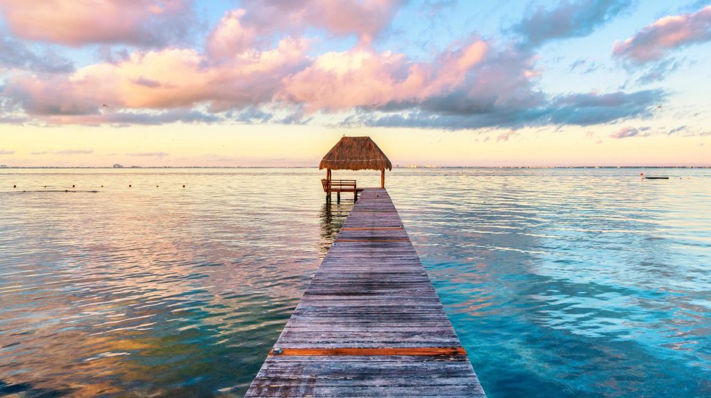 Beautiful pink and white Clouds and blue calm ocean with a pier at sunset in the Florida Keys. FloridaKeysVillas.com